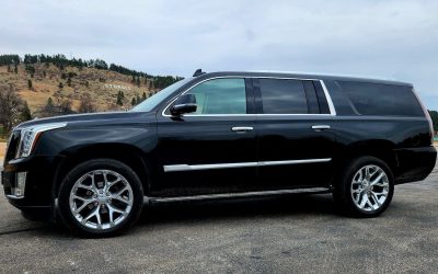 Side view of Cadillac SUV with "Sturgis" sign in background